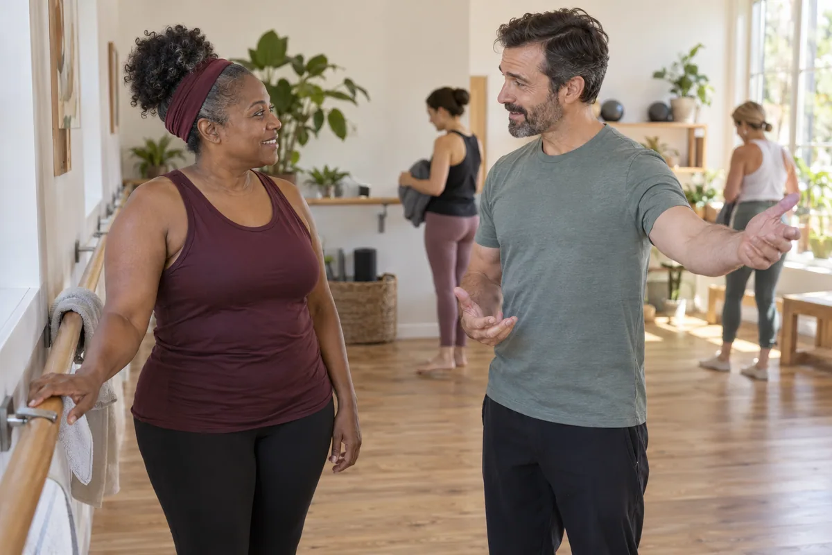 Adult participant discussing a barre class with an instructor before joining.